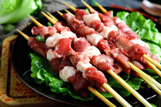 Raw Meat Kebabs on Skewers with Fresh Lettuce Ready for Grilling