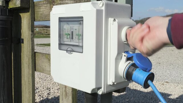 Person connecting and disconnecting caravan electric hook up point