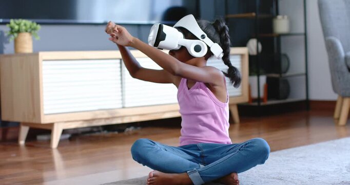 African American child wearing white VR headset reaching and manipulating VR objects in living room