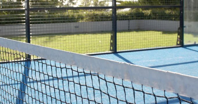 Camera is shifting laterally, framing court net diagonally and showing net wear and court lines