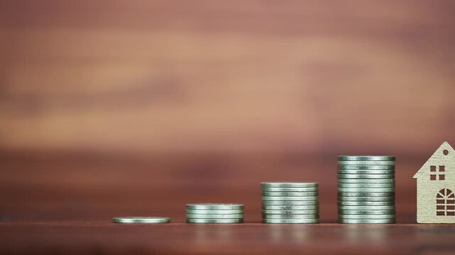 Coins next to a house, real estate investment growth and mortgage savings concept or background