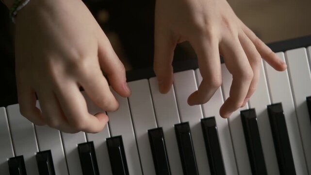 Teenager playing a synthesizer keyboard. Hands wearing colorful bracelets and friendship bands move across the keys, highlighting youth creativity and music education. Clean overhead, learning modern 