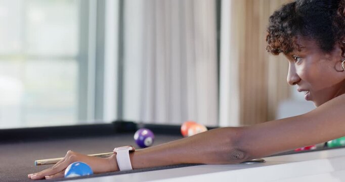 African American females watching woman taking turn aiming cue on pool table in yellow top