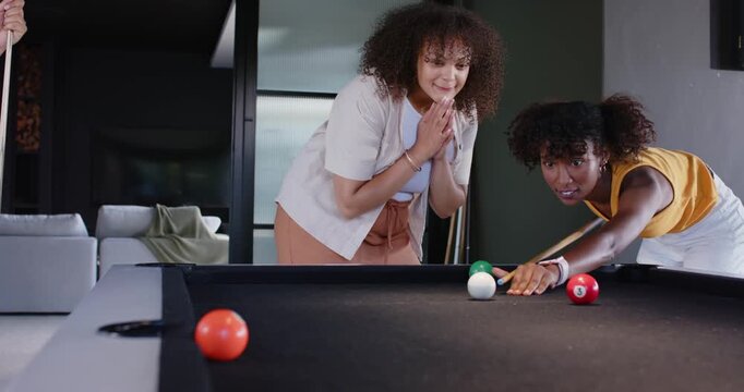 African American women friends playing on black felt table at home spotting pocket celebrating