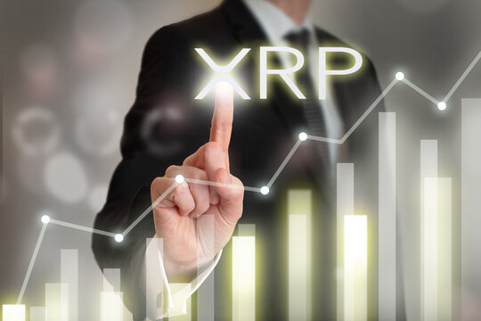 Businessman pushing digital XRP button and digital graphics while crypto market is going up.