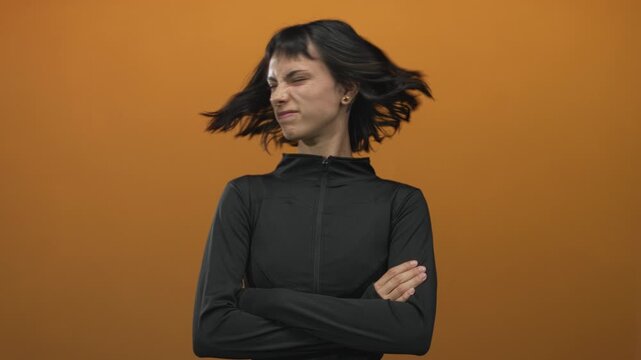 Woman in black zip jacket sportswear with arms crossed shakes head in studio; resilience frustration.