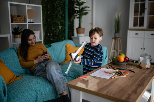 Mother ignoring child playing with toy airplane