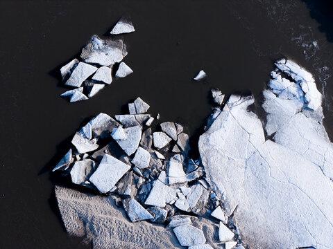 Aerial view of ice floes fractured in the Vistula River, their stark white contrasting against the dark water, Warszawa, Masovian Voivodeship, Poland.