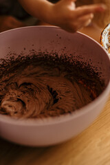 Mixing chocolate frosting in pink bowl for baking
