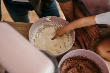 Little hand tasting sweet frosting from mixing bowl