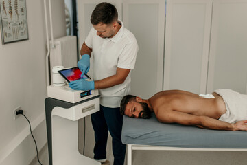 Physiotherapist using technology for back treatment on client