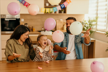 Family celebrating birthday with daughter and balloons