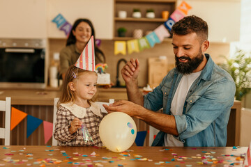 Celebrating child birthday with father and mother preparing cake
