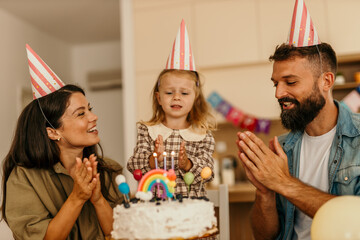 Family celebrating child's birthday at home with cake