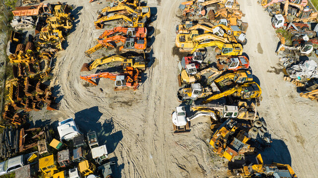 Aerial view of rows of heavy construction equipment, a symphony of yellow and orange hues amidst the landscape, Nanclares de la Oca, Basque Country, Spain.