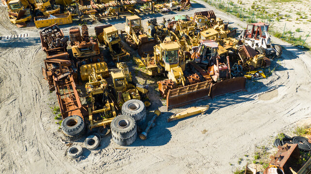 Aerial view of a sprawling junkyard of heavy construction equipment, a symphony of rusted metal and decaying rubber under the open sky, Nanclares de la Oca, Basque Country, Spain.