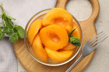 Pickled peaches and mint leaves in bowl on light grey table, flat lay © New Africa