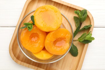 Pickled peaches and mint leaves in bowl on white wooden table, top view © New Africa