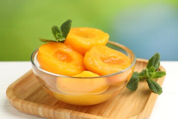 Pickled peaches and mint leaves in bowl on white wooden table, closeup © New Africa