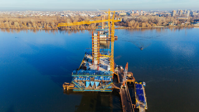 Aerial view of a vibrant construction site on the water featuring a towering crane and the developing structure, Novi Sad, Vojvodina, Serbia.