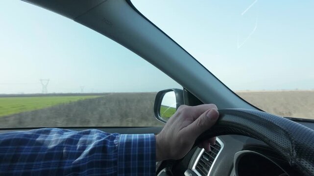 closeup of man's hand on steering wheel while driving
