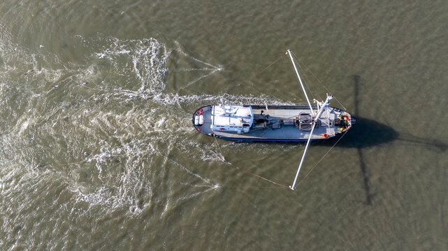 Aerial view of a fishing vessel cutting through the sea, leaving a frothy wake behind, Wijk aan Zee, North Holland, Netherlands.