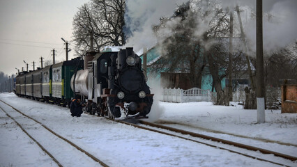 A narrow-gauge railway.A steam locomotive at a railway station. A winter, tourist, retro voyage. A steam locomotive in all its glory. Rolling stock at a railway station.  © Valerii
