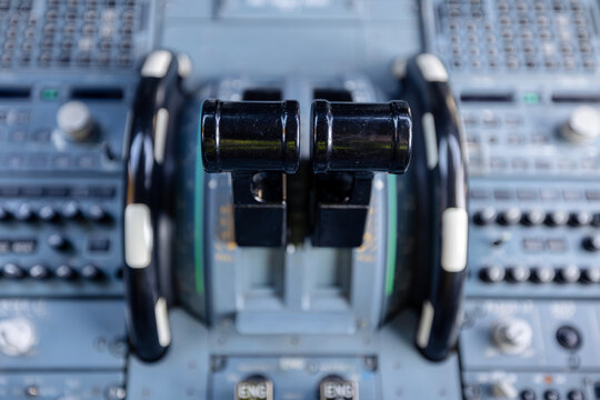Close-up view of engine throttle levers inside commercial airplane cockpit. Aviation control, flight operation, pilot workspace, technology, and transportation concept.