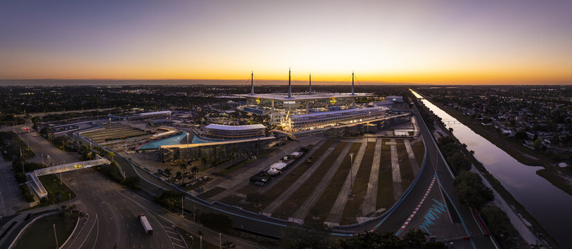 Miami Gardens, USA - 23 February 2026: Aerial view of Hard Rock Stadium bathed in the soft glow of dawn, a modern arena amidst urban sprawl.