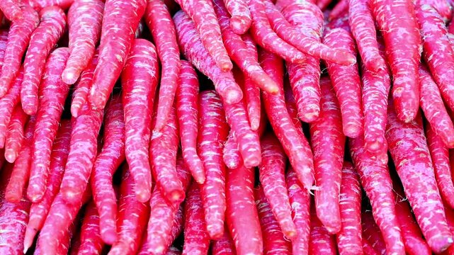 Slow Motion Shot of Red carrots arranged tightly together as a food pile, displayed in a market stall with a vibrant color palette and close-up angle at 180 fps High quality footage