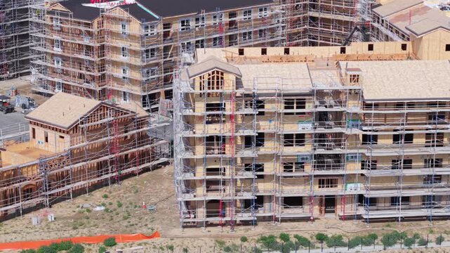 Construction workers build a residential building with earthquake resistant techniques using scaffolding at a project site.