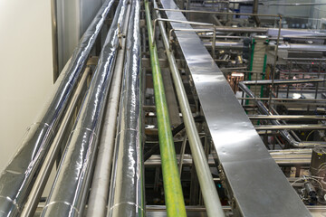 Industrial factory interior featuring metal pipelines and conveyor belt systems