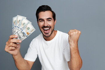 Happy man celebrating success with money in hand, wearing casual white t-shirt, showing excitement...