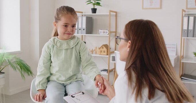 Kind caring pediatrician talking to diagnose little girl in clinic, treat and provide care for baby kid physical, mental care and behavioral development, helping, hospital supporting patient