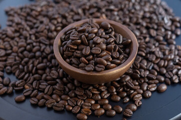 Artisan roasted coffee beans in a wooden bowl on a dark textured background