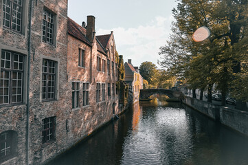 Naklejka premium Scenic canals and historic medieval architecture in Bruges, Belgium, featuring traditional Flemish buildings along the water in the iconic European city.