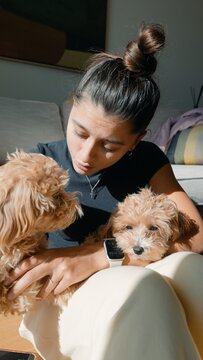 Woman kisses puppy. Woman shares affection with puppy on sofa
