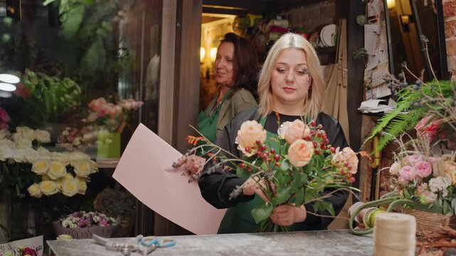 White florist demonstrating bouquet binding technique, trainer and apprentice practicing wire and tape methods, careful trimming of stems, stepbystep layout on counter, laughter and focused hands
