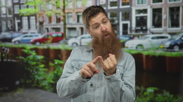 Man with long red beard pointing finger to hand on city street; self reflection introspection contemplation.