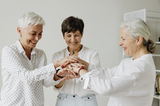 Three mature women stacking hands together in unity