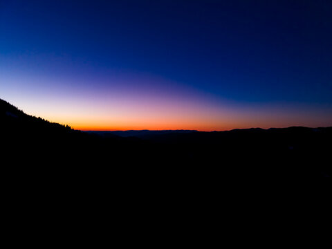 Colorful sky at sunset over mountains with clear horizon and fading light in the evening