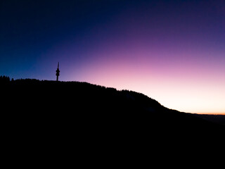 View of a tower on a mountain at dusk with a gradient sky transitioning from dark blue to light purple