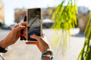 girl walks around old city in arab country and takes photos for social networks. girl with phone takes photo of palm tree.