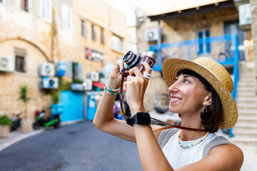Cheerful smiling woman walking along the street of the old city in an Arab country and taking pictures of sights for social networks. Girl with a phone.