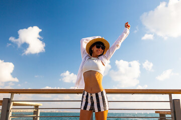 The girl enjoys her vacation. A slender woman stands on the embankment near the sea and enjoys the moment. Summer vacation by the sea.