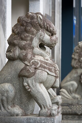 Naklejka premium A traditional Chinese stone lion sculpture in a majestic crouching pose guarding an entrance