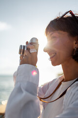 Girl taking pictures. Beautiful tourist enjoying sea view during weekend vacation and taking a picture with film camera. Girl with camera.
