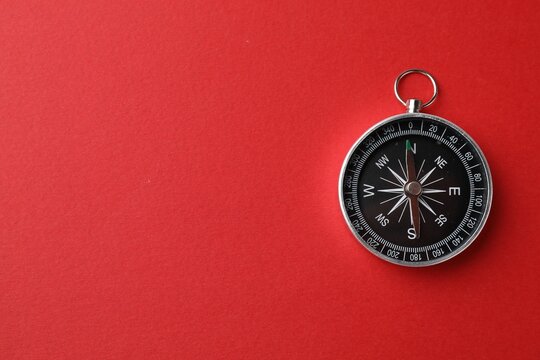 One compass on red background, top view. Space for text