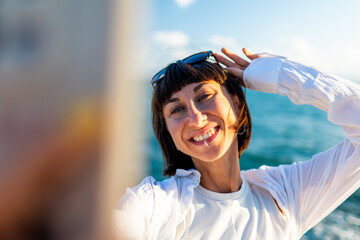 Female blogger shoots content for social networks. Smiling tourist takes a selfie on her mobile phone against the backdrop of the sea.