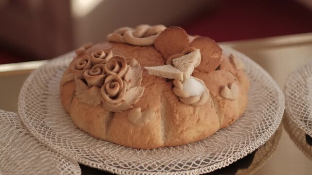 Traditional Slavic wedding bread korovai decorated with dough roses and salt on a lace doily